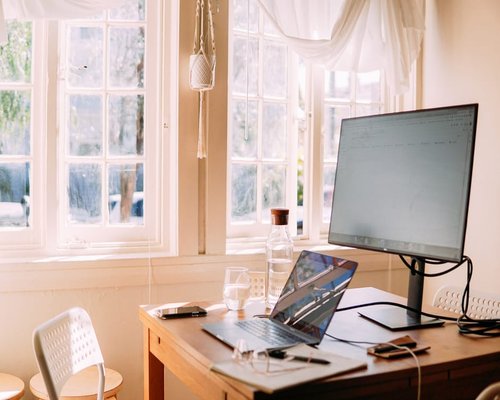Comfortable bright remote workspace with wooden desk and natural window light